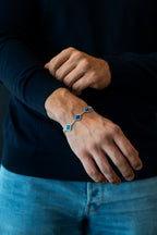 Person wearing a blue bracelet on a dark background