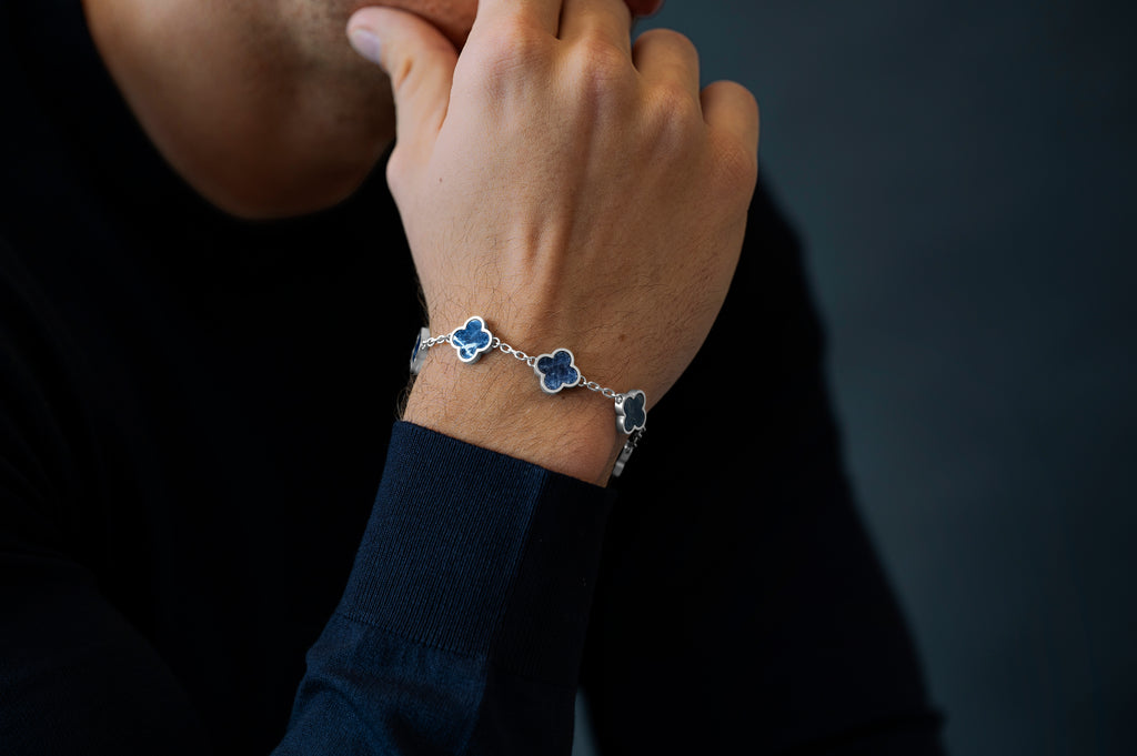 Person wearing a bracelet with blue flower charms on a dark background
