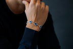 Person wearing a bracelet with blue flower charms on a dark background