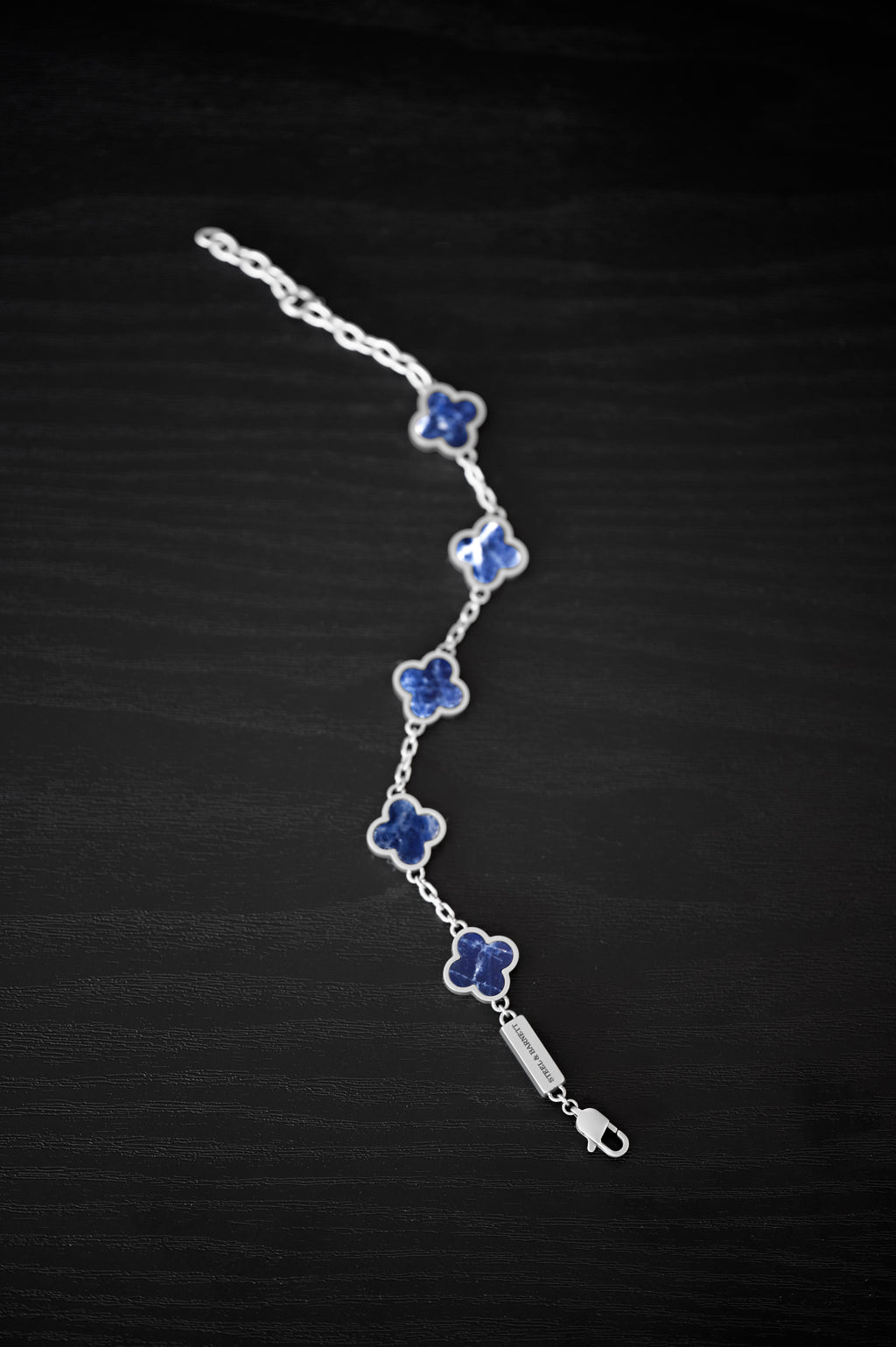 Silver bracelet with blue flower-shaped charms on a black background