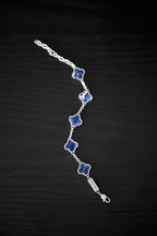 Silver bracelet with blue flower-shaped charms on a black background